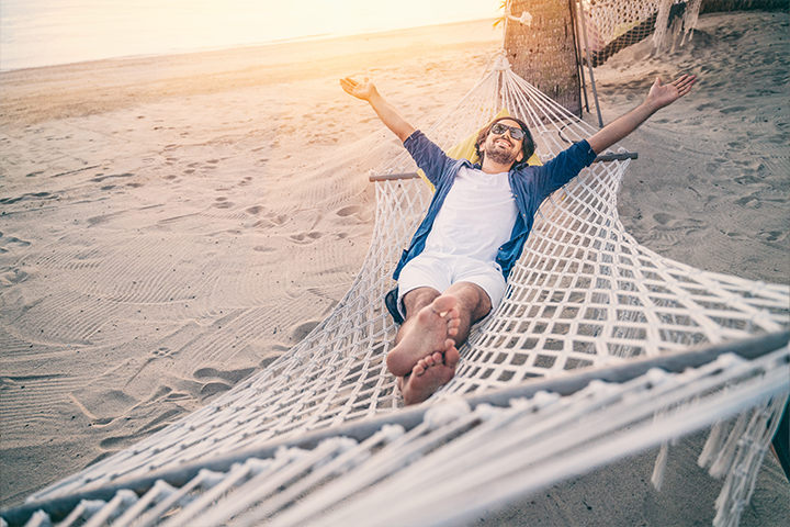 man relaxes in hammock on the beach