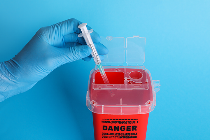 putting syringe in sharps container