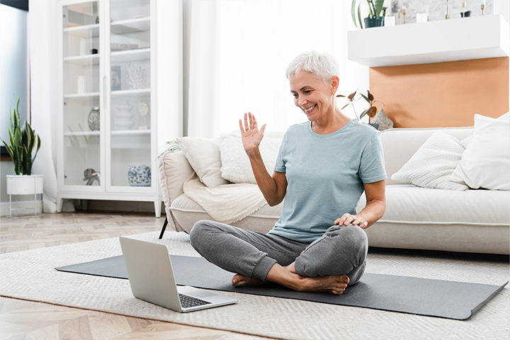 older woman doing workout video on yoga mat