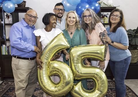 friends celebrate a 65th birthday with gold balloons