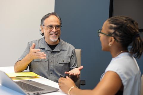 Teacher and student have conversation at a work desk