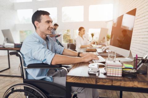 man sits in wheelchair while working at desk
