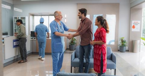 couple shakes hands with doctor in medical lobby