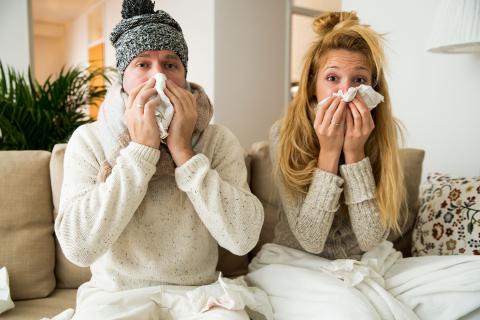 young couple with a cold bundled up with tissues