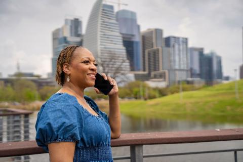 woman talks on phone in front of Austin skyline