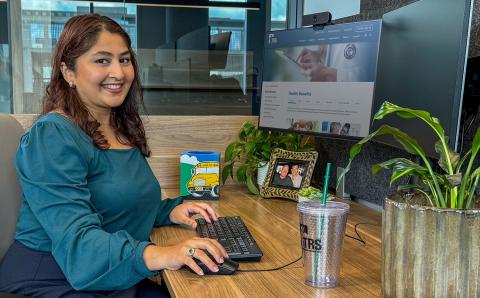 woman sits at desk while working on computer