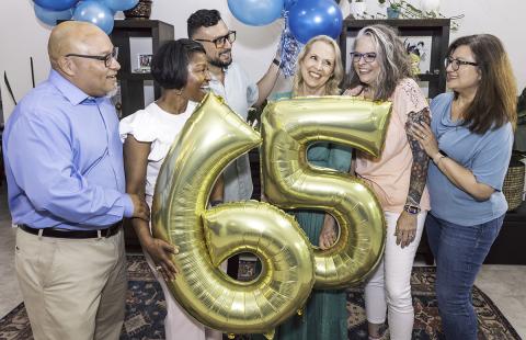 friends celebrating a 65th birthday with gold balloons
