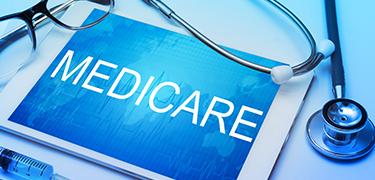 Computer tablet with Medicare typed out next to a stethoscope and pair of eyeglasses